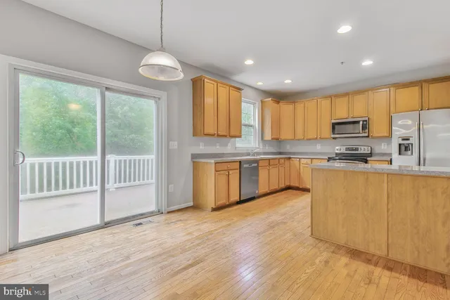 a kitchen with stainless steel appliances granite countertop a stove a sink dishwasher and a refrigerator with wooden floor