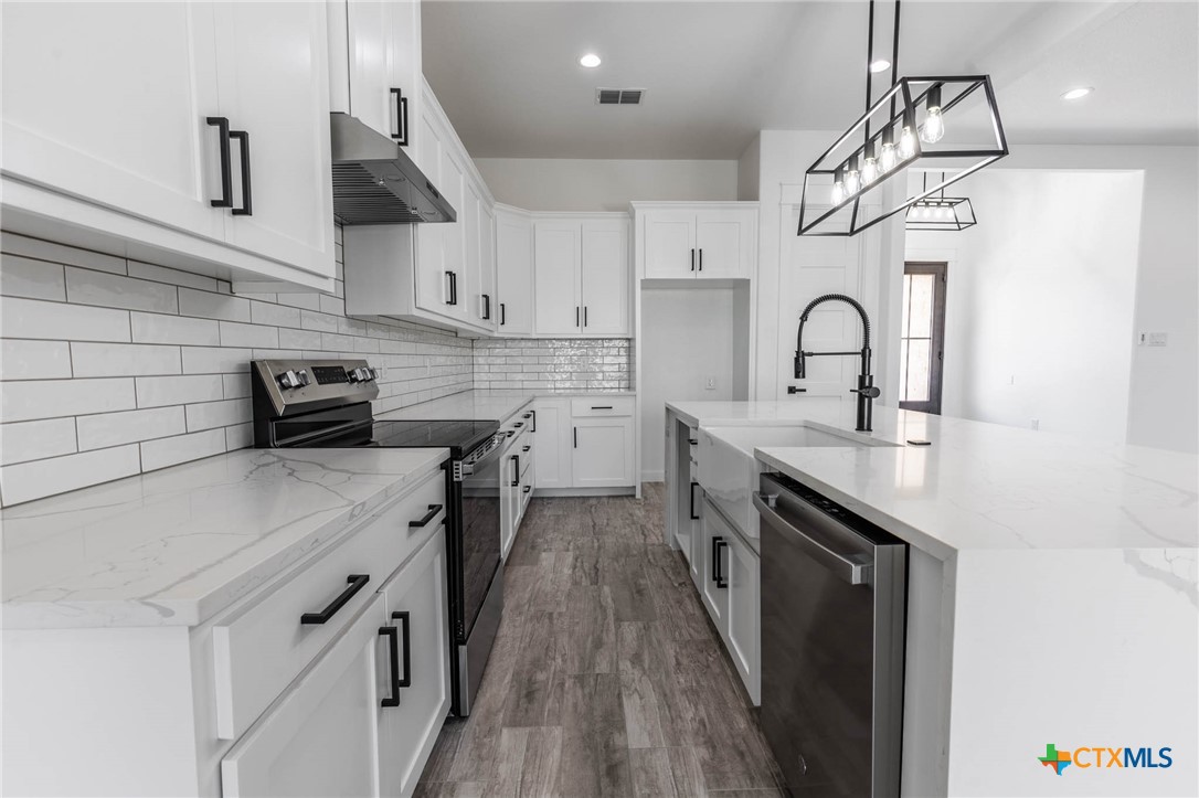 110 Lake Village Road Seguin, TX 78155 - Photo 14 of 38 a kitchen with stainless steel appliances a sink dishwasher and white cabinets with wooden floor