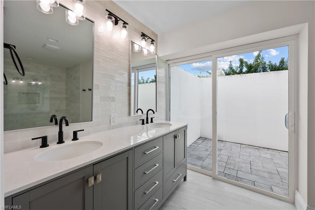 4611 Crayton Road Naples, FL 34103 - Photo 20 of 38 a bathroom with a double vanity sink and mirror