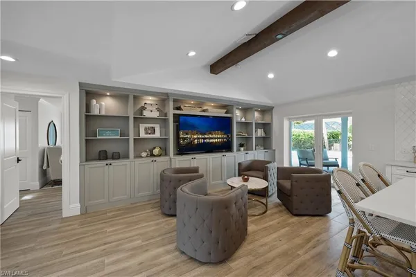 a living room with furniture a flat screen tv and wooden floor