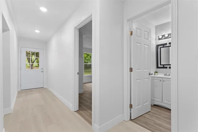 an empty room with wooden floor chandelier fan and windows