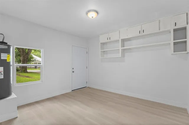a view of an empty room with wooden floor and windows