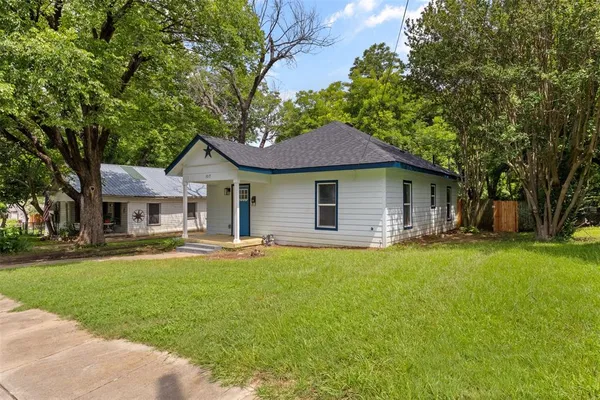 a front view of a house with a garden and trees