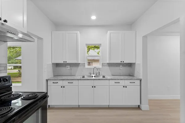 a kitchen with granite countertop white cabinets stainless steel appliances and a sink