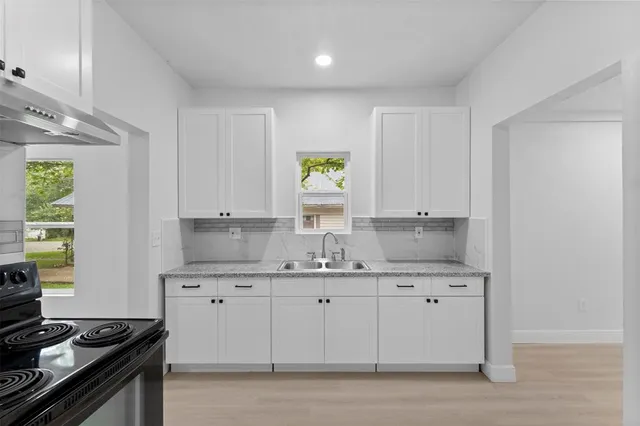 a kitchen with granite countertop white cabinets stainless steel appliances and a sink