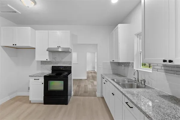 a kitchen with granite countertop a sink stove and refrigerator