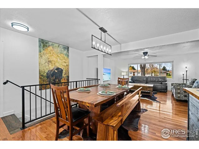 a view of a dining room and livingroom with furniture wooden floor a rug a painting and a chandelier