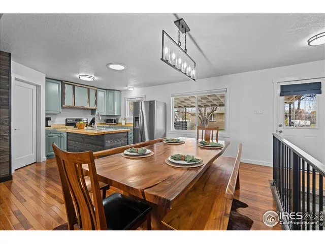 a view of a dining room and livingroom with furniture wooden floor a rug a painting and a chandelier