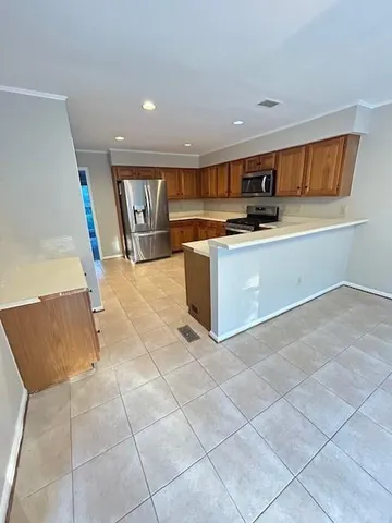 a kitchen with stainless steel appliances kitchen island granite countertop a refrigerator and a stove top oven