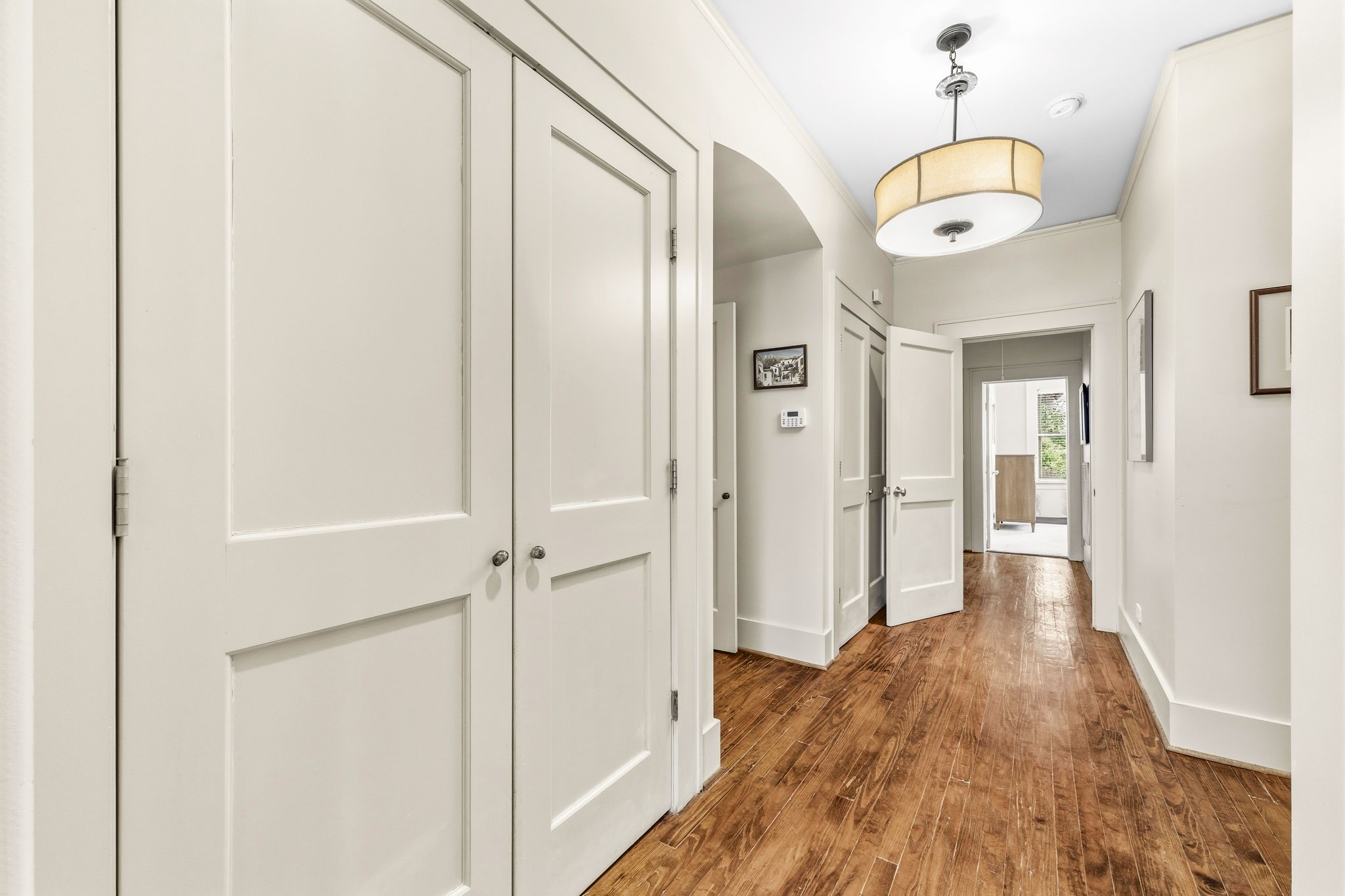 1521 Kipling Street Houston, TX 77006 - Photo 20 of 35 Bright, welcoming hallway with polished hardwood floors and ample storage. Features elegant light fixture and leads to a well-lit room with large windows.