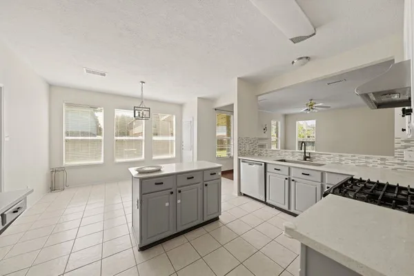 a large white kitchen with a stove a sink a window and dining table