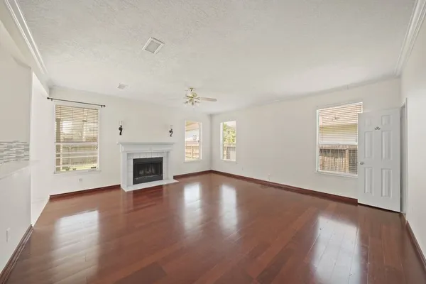 an empty room with wooden floor fireplace and windows