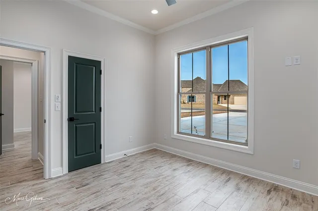 an empty room with wooden floor closet and windows