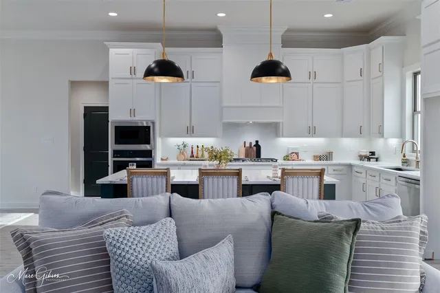 a kitchen with stainless steel appliances granite countertop a stove a sink a microwave a refrigerator and white cabinets