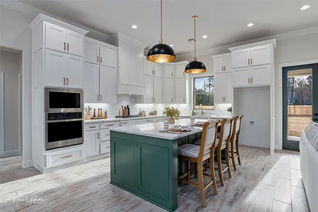 a kitchen with stainless steel appliances granite countertop a stove a sink a microwave a refrigerator and a dining table with wooden floor