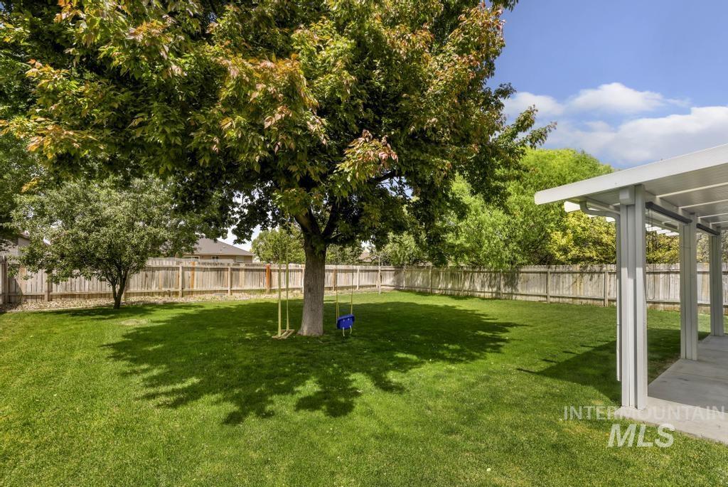 1183 Cortes Loop Twin Falls, ID 83301 - Photo 28 of 30 Spacious backyard featuring a large tree providing shade over a manicured lawn, a concrete patio with an attached pergola, and a privacy fence enclosing the perimeter