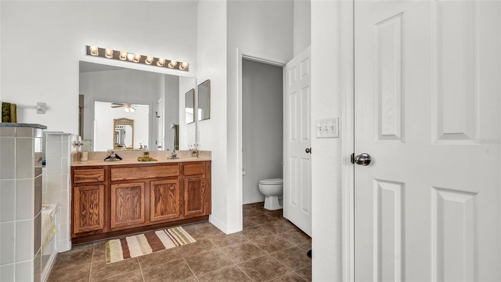 1153 Legatto Loop Dundee, FL 33838 - Photo 23 of 48 a spacious bathroom with a mirror a sink and a toilet