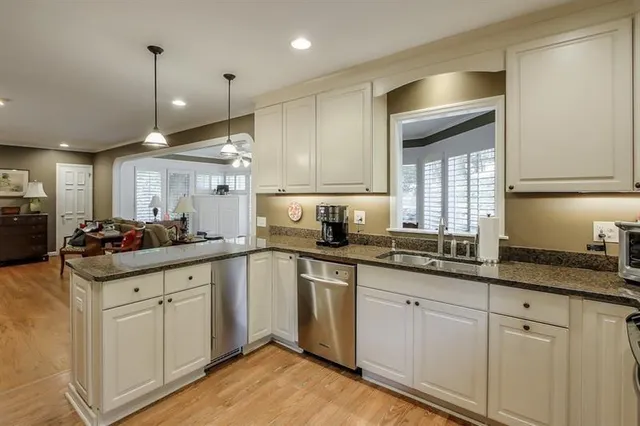 a kitchen with granite countertop a sink stainless steel appliances and cabinets