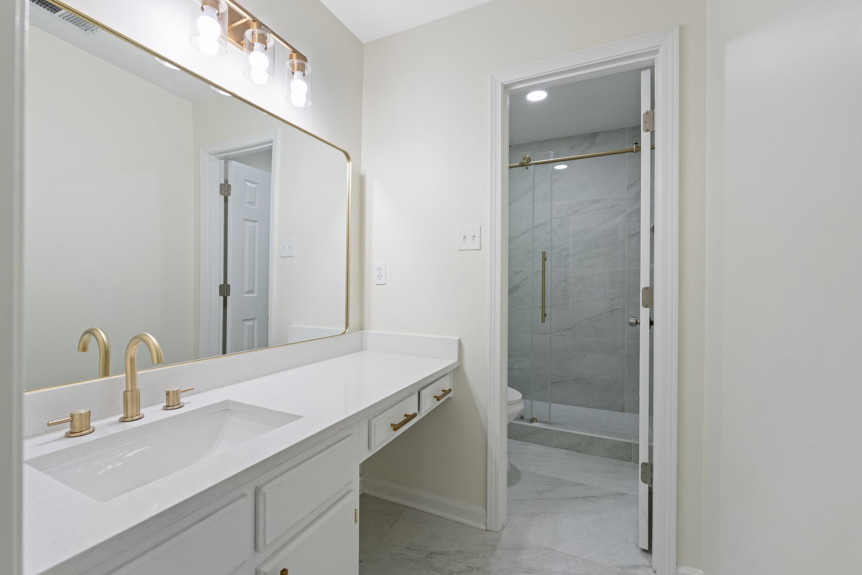 6400 Saginaw Road Memphis, TN 38134 - Photo 13 of 27 Beautifully updated primary bath featuring a granite vanity with makeup area, designer lighting, modern fixtures, tile flooring, and a clean, sophisticated design.