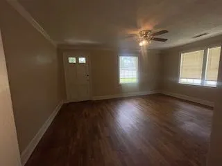 a view of an empty room with wooden floor and a window