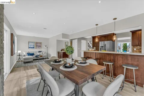 a view of a dining room and livingroom with furniture wooden floor a rug a fireplace and a chandelier