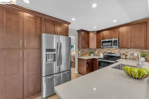 a kitchen with stainless steel appliances granite countertop a refrigerator a stove top oven a sink and dishwasher