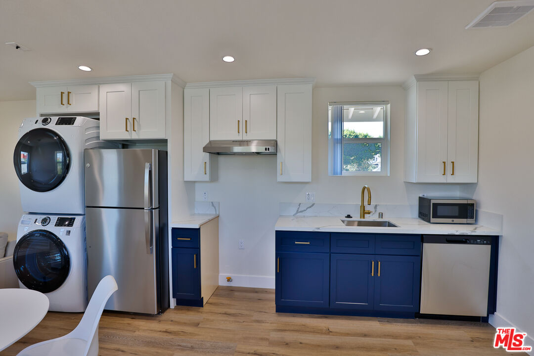 1237 West 25th Street, Unit 1241 1/2 Los Angeles, CA 90007 - Photo 3 of 16 a kitchen with stainless steel appliances granite countertop a refrigerator a stove a sink dishwasher and white cabinets with wooden floor