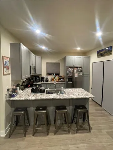 a kitchen with stainless steel appliances granite countertop a dining table chairs sink refrigerator and cabinets