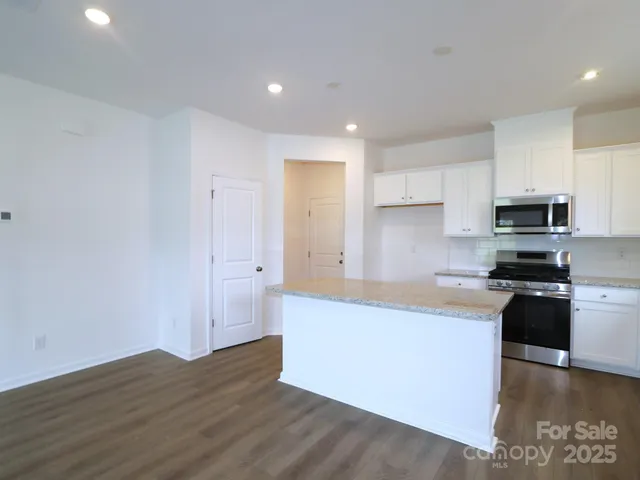 a kitchen with granite countertop a refrigerator and a stove top oven