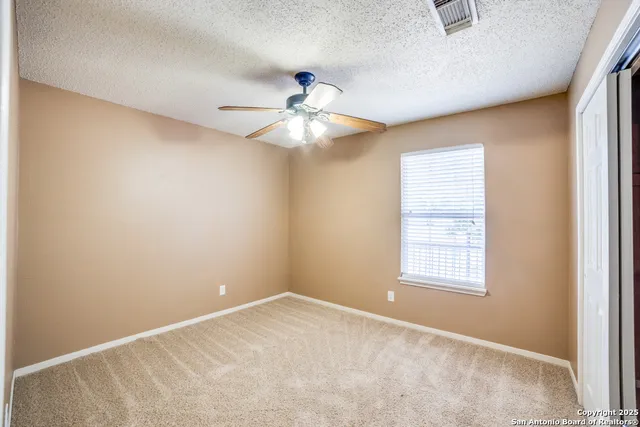 an empty room with windows and fan