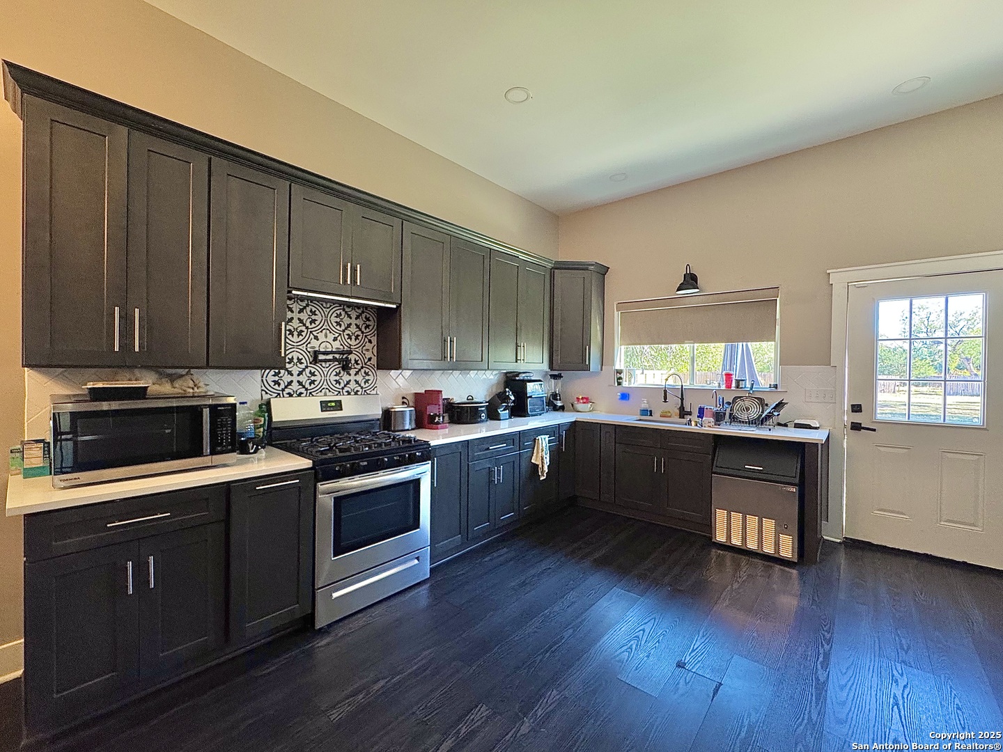 1106 North High Street Uvalde, TX 78801 - Photo 14 of 26 a kitchen with stainless steel appliances kitchen island granite countertop wooden floors and sink