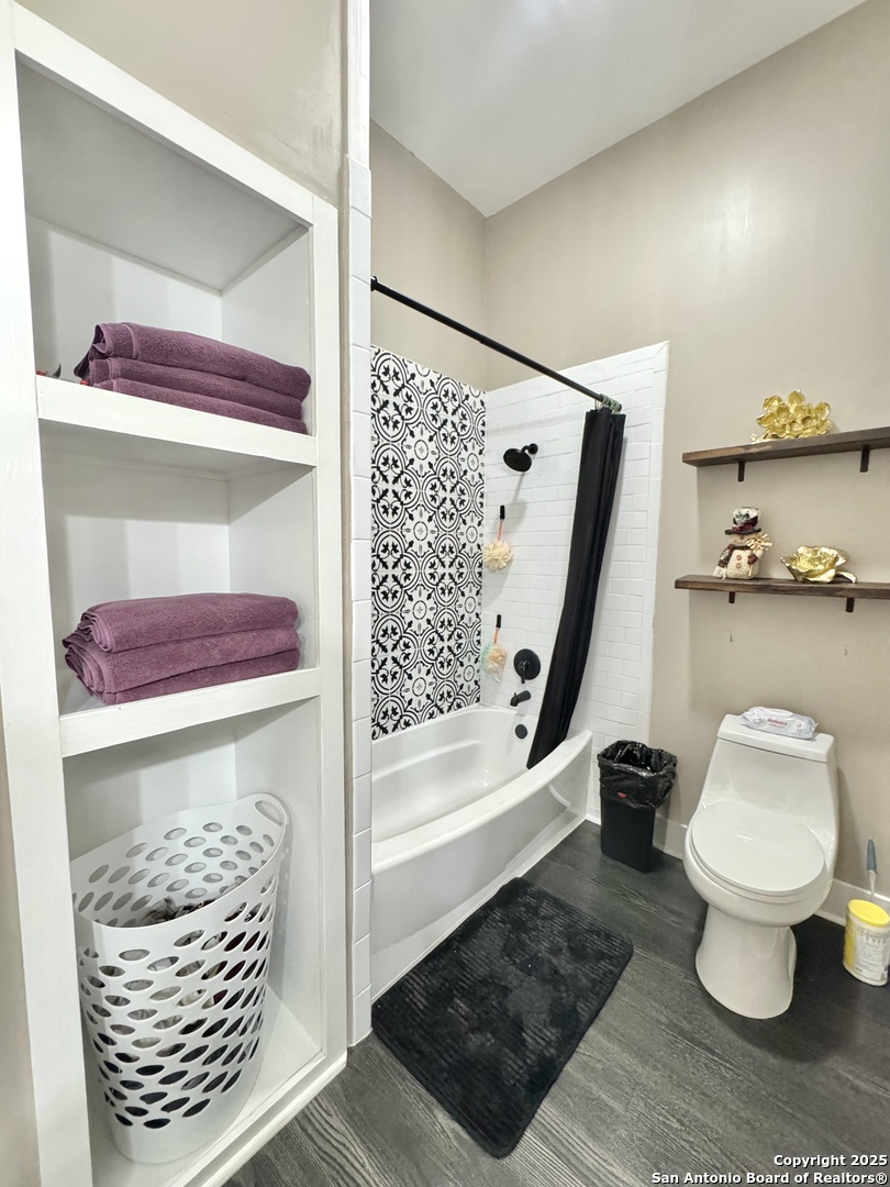 1106 North High Street Uvalde, TX 78801 - Photo 8 of 26 a bathroom with a toilet and a shower curtain