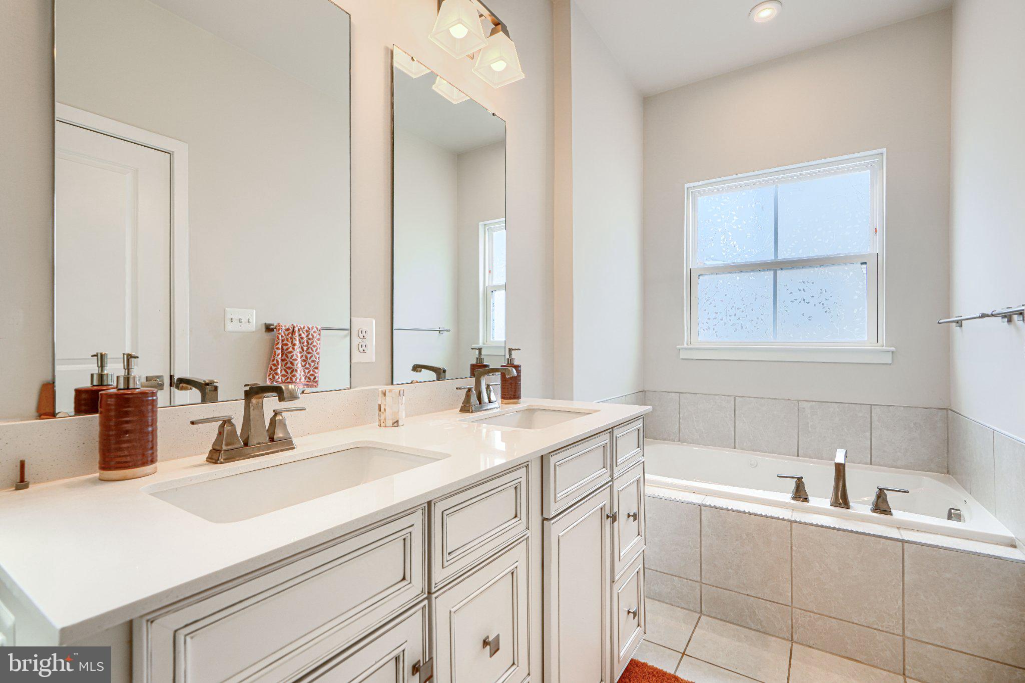 1510 Decatur Street Baltimore, MD 21230 - Photo 19 of 27 a bathroom with double vanity sinks a mirror and a bathtub