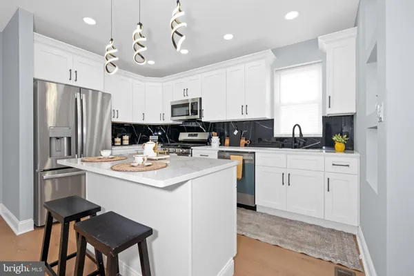 a kitchen with kitchen island a white cabinets and refrigerator