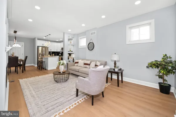 a living room with furniture potted plant and kitchen appliances