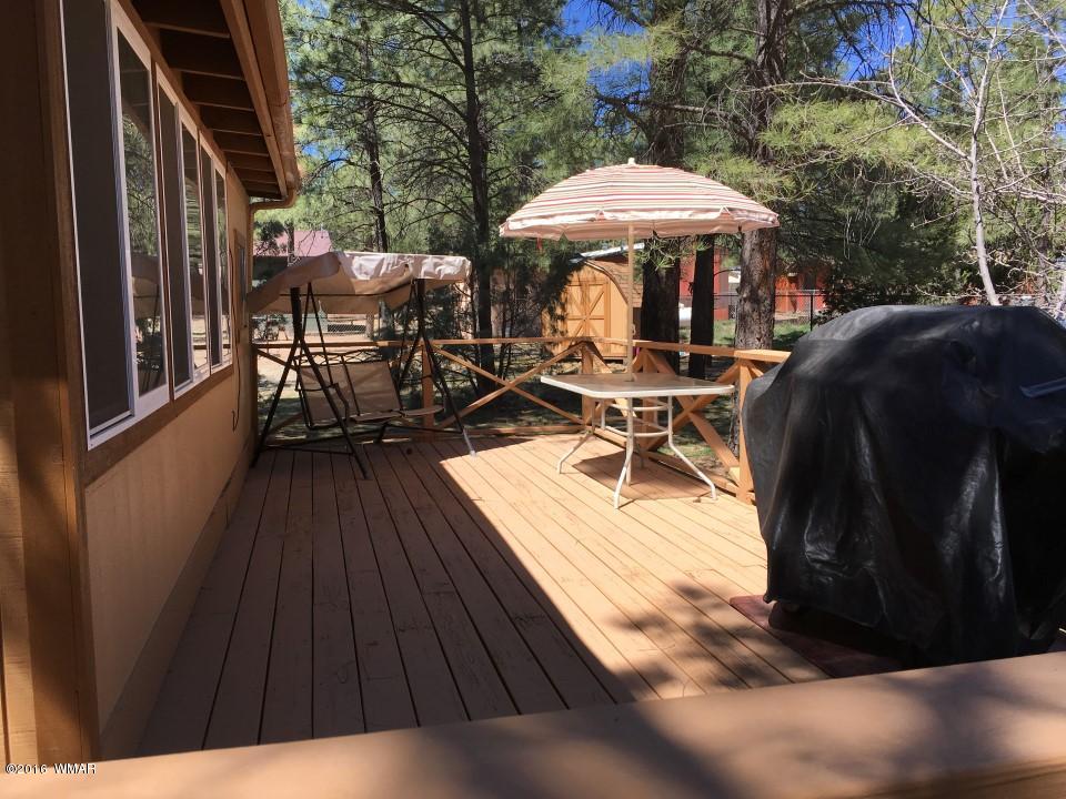 2846 Timber Trail Loop Overgaard, AZ 85933 - Photo 3 of 16 a view of a patio with table and chairs under an umbrella with wooden floor