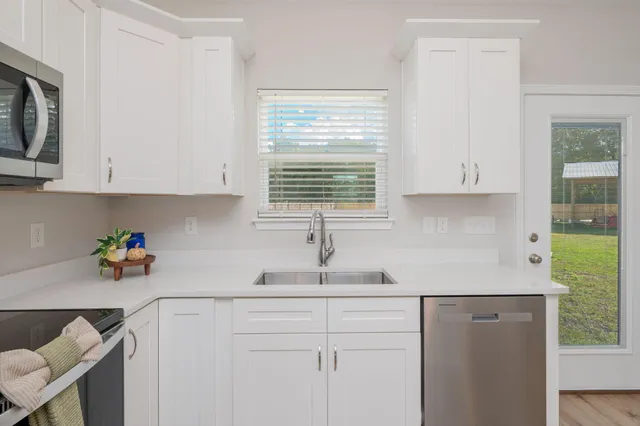 a kitchen with stainless steel appliances white cabinets and a window