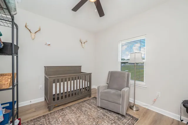 a room with lots of white furniture and wooden floor