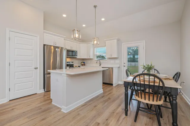 a kitchen with a table chairs refrigerator and cabinets