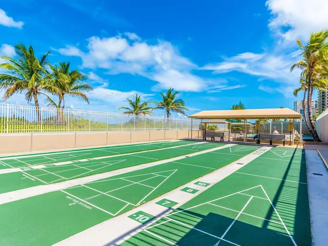 a view of a swimming pool with a yard and palm trees