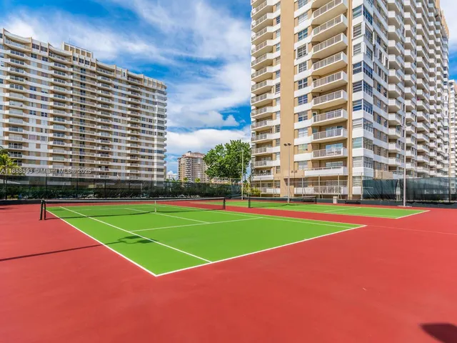 a view of a tennis ground with large trees