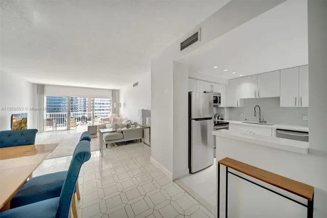 a living room with furniture and a large window with kitchen view