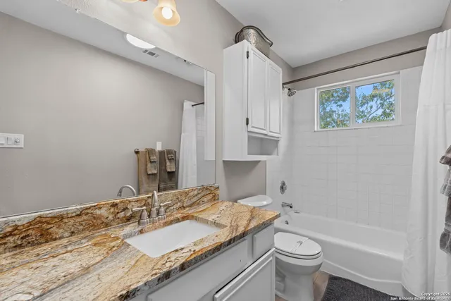 a bathroom with a granite countertop sink a toilet and bathtub