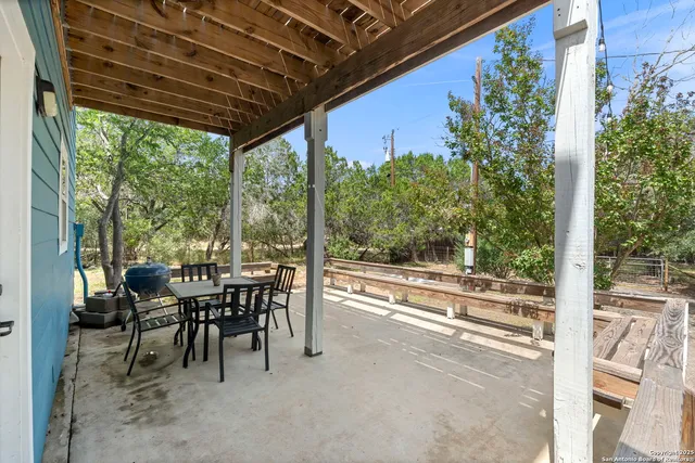 a view of a patio with table and chairs and floor to ceiling window plants and trees