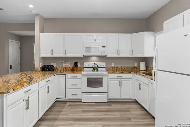 a kitchen with granite countertop white cabinets and white appliances