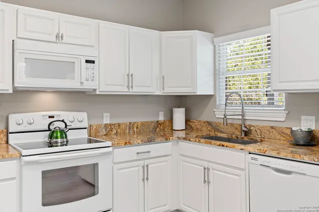 a kitchen with white cabinets and a white stove