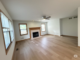416 Fawn Lane Oswego, IL 60543 - Photo 9 of 13 an empty room with windows fireplace and wooden floor