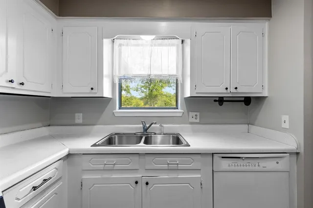 a kitchen with white cabinets and a window