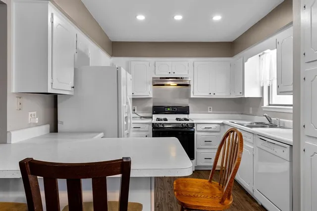 a kitchen with stainless steel appliances granite countertop a stove a refrigerator a sink a dining table and chairs