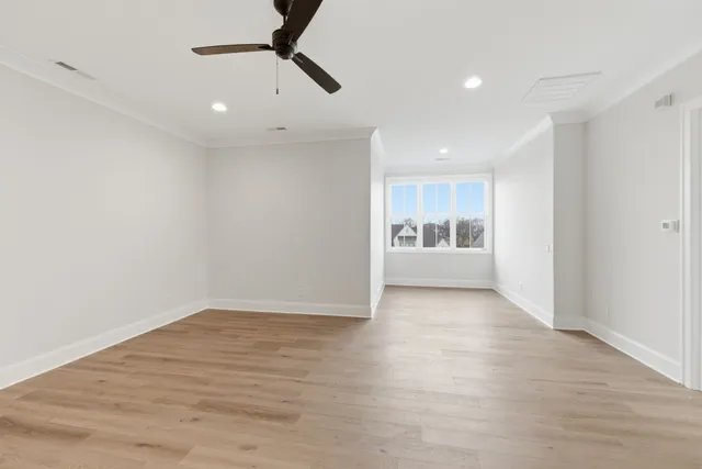 a view of an empty room with window and wooden floor